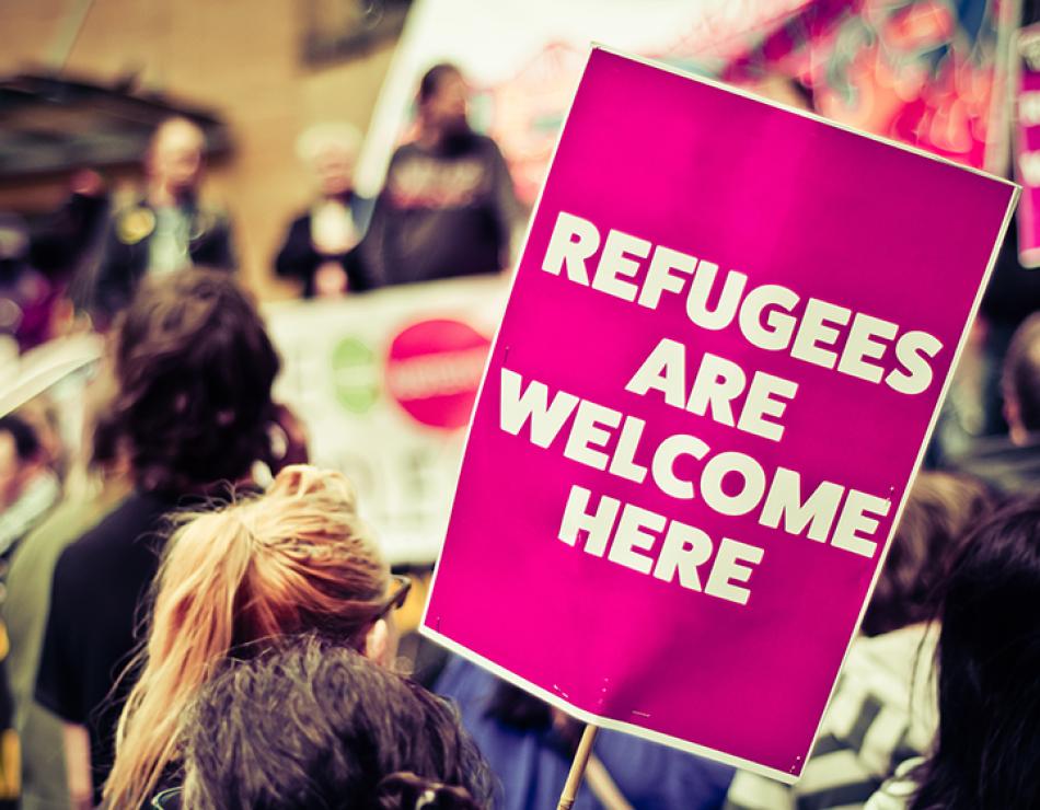 groupe de personnes avec un panneau : "Refugees are welcome here"